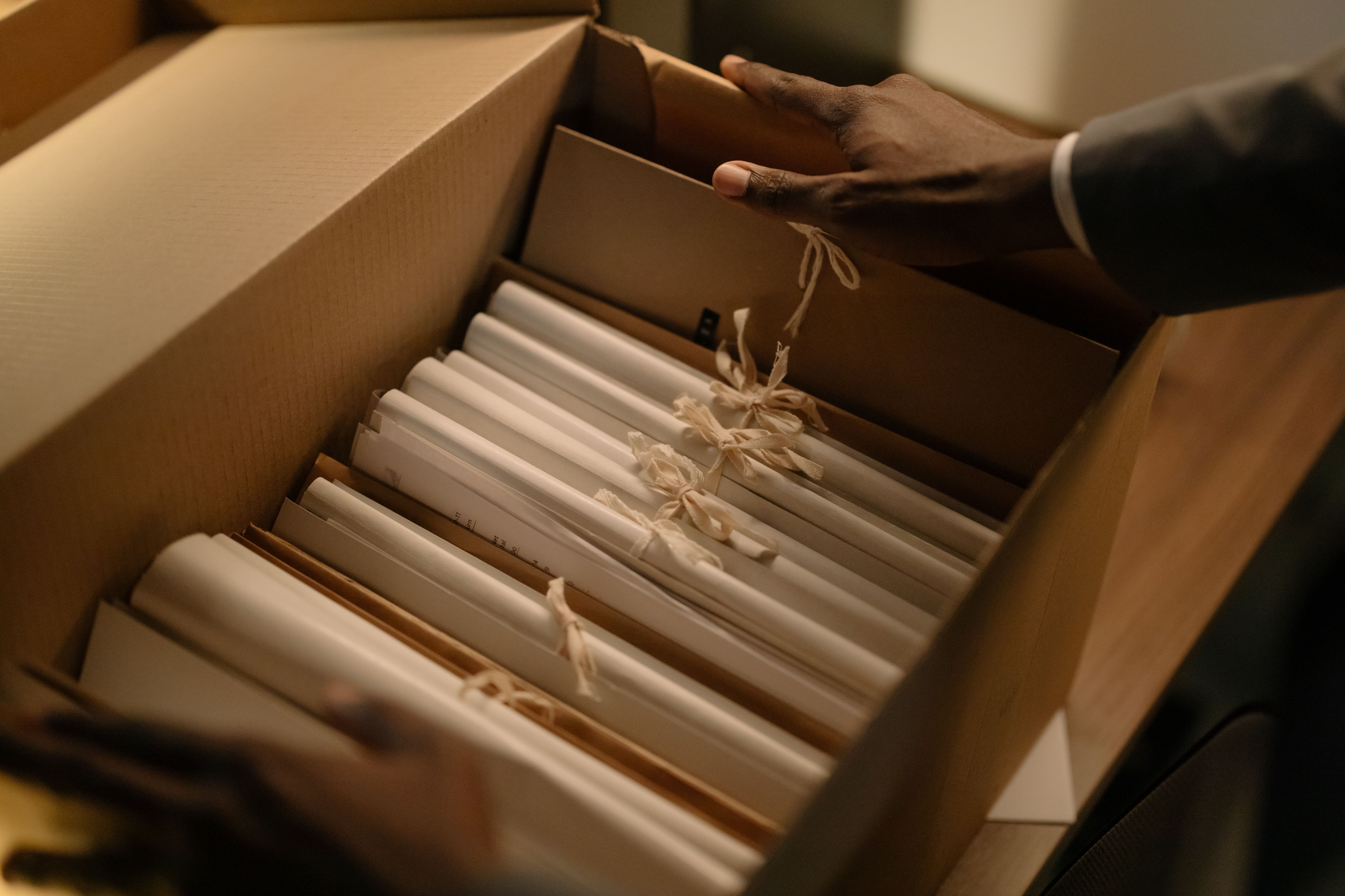 Hands organizing files in a box, symbolizing evidence gathering and case file management for complex litigation