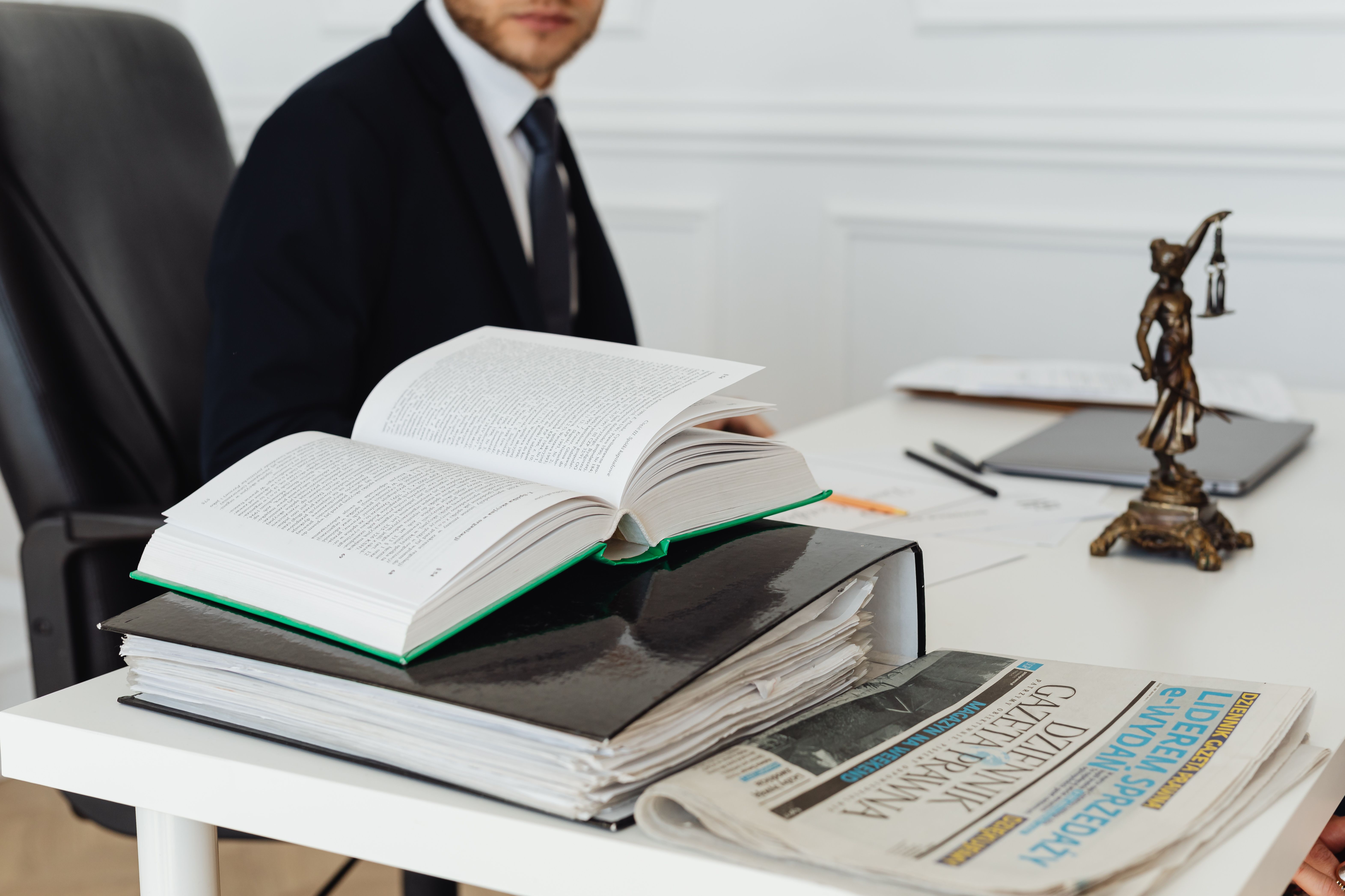 A lawyer sitting at a desk with legal books and documents, embodying a law firm managing large cases