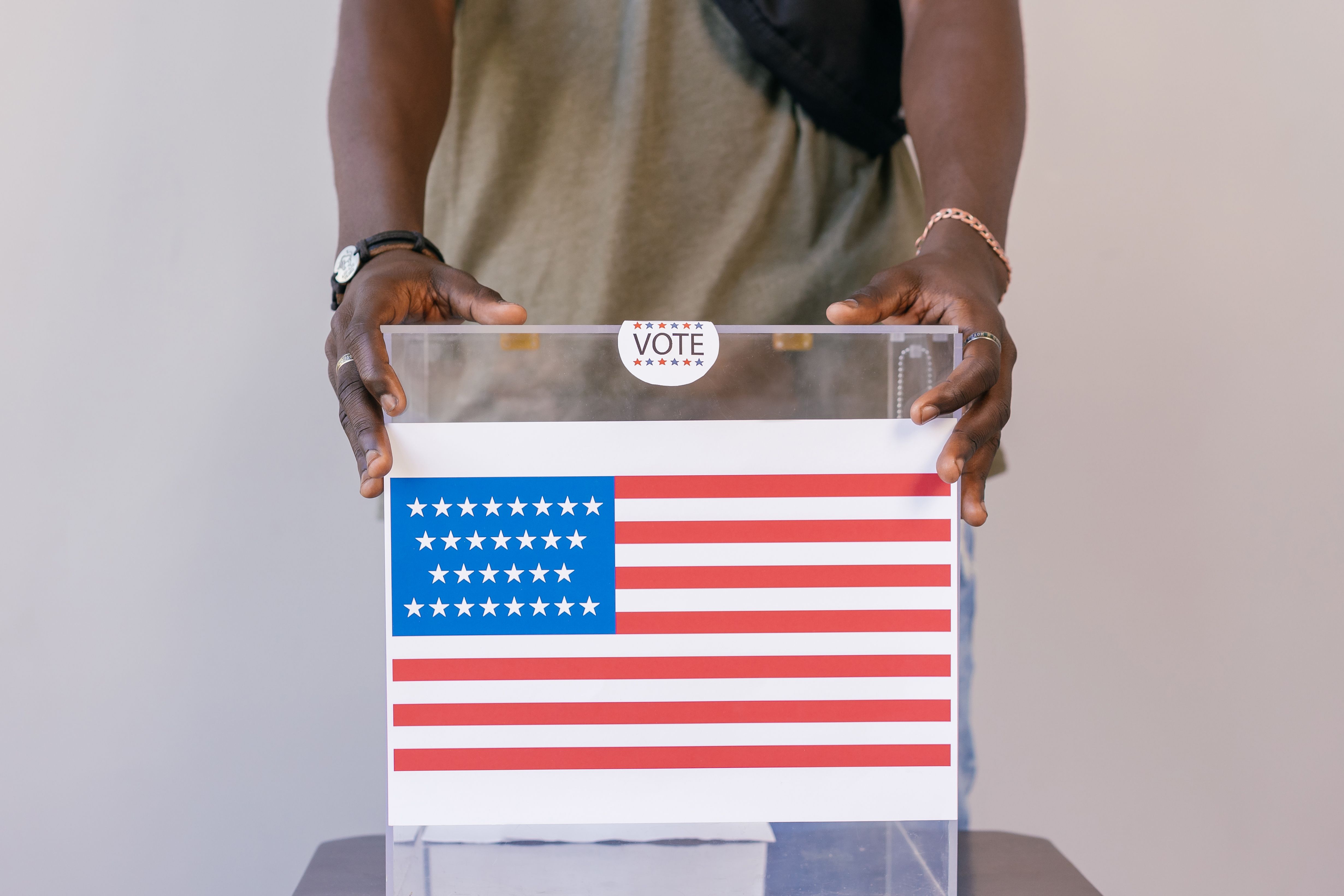 A voter placing a ballot in a transparent ballot box, symbolizing civic participation and accountability.